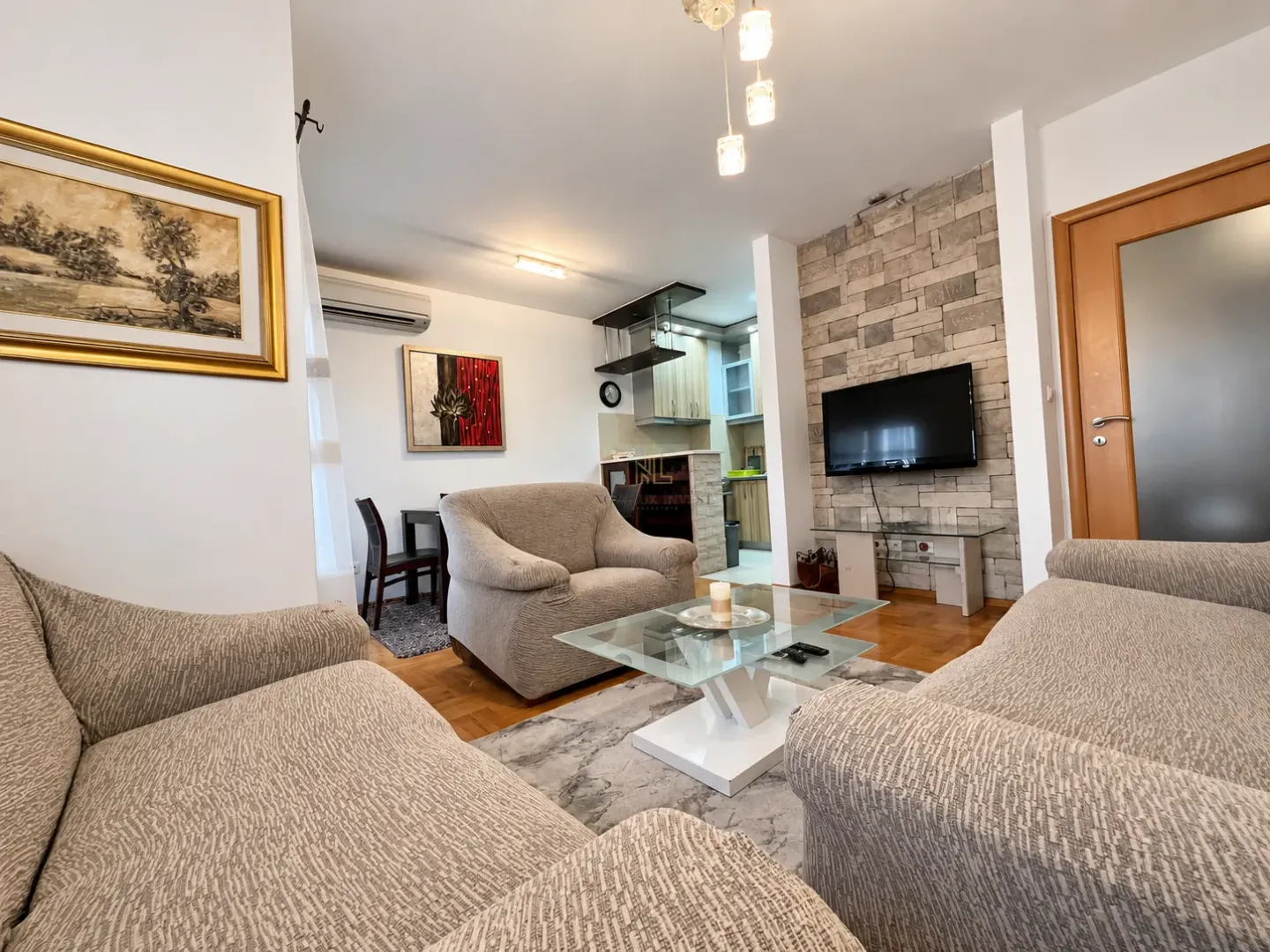 Spacious living room with a sofa set, coffee table, and a view of the kitchen in the background.