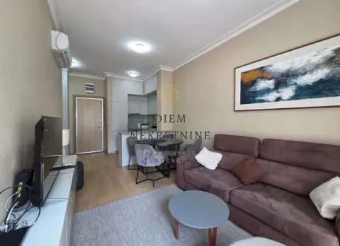 Living room with a sofa, dining area, and kitchen in the background. - image 2