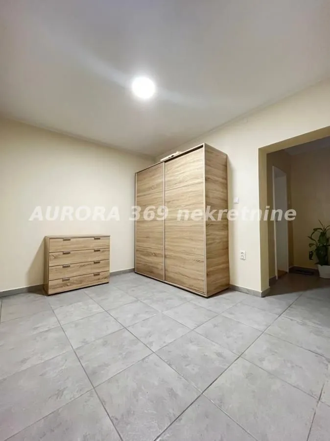 Manja spavaća soba sa velikim drvenim plakarom i komodom.