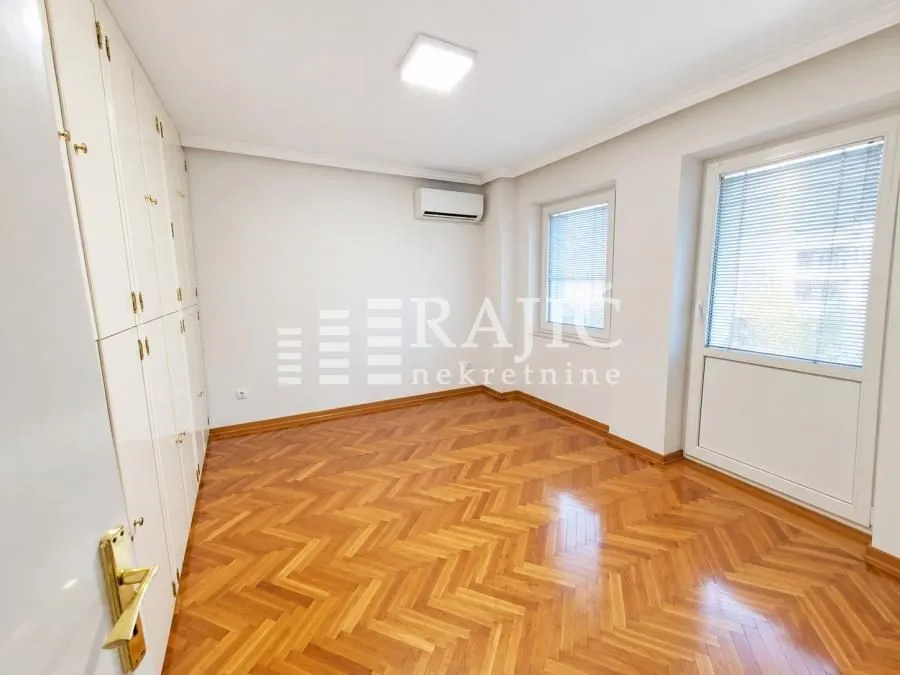 Empty bedroom with built-in wardrobes and wooden parquet flooring.