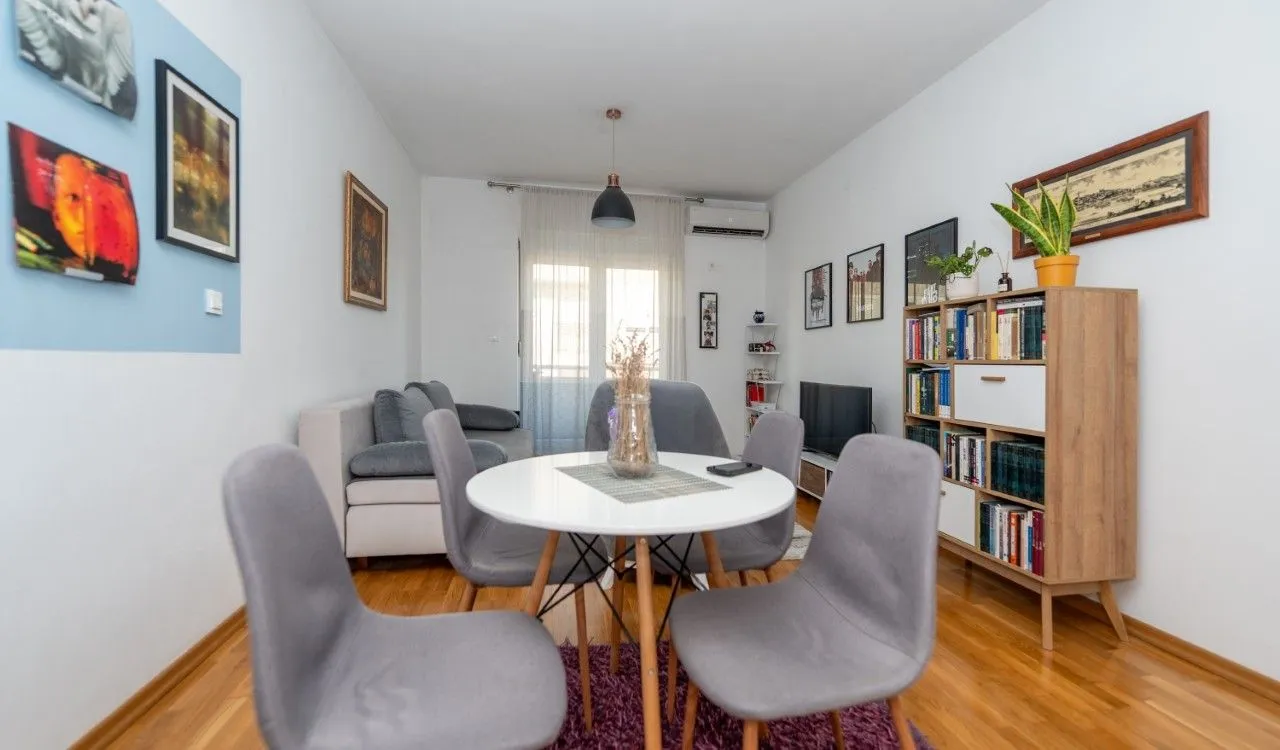 Living room with a dining table, sofa set, and bookcase.