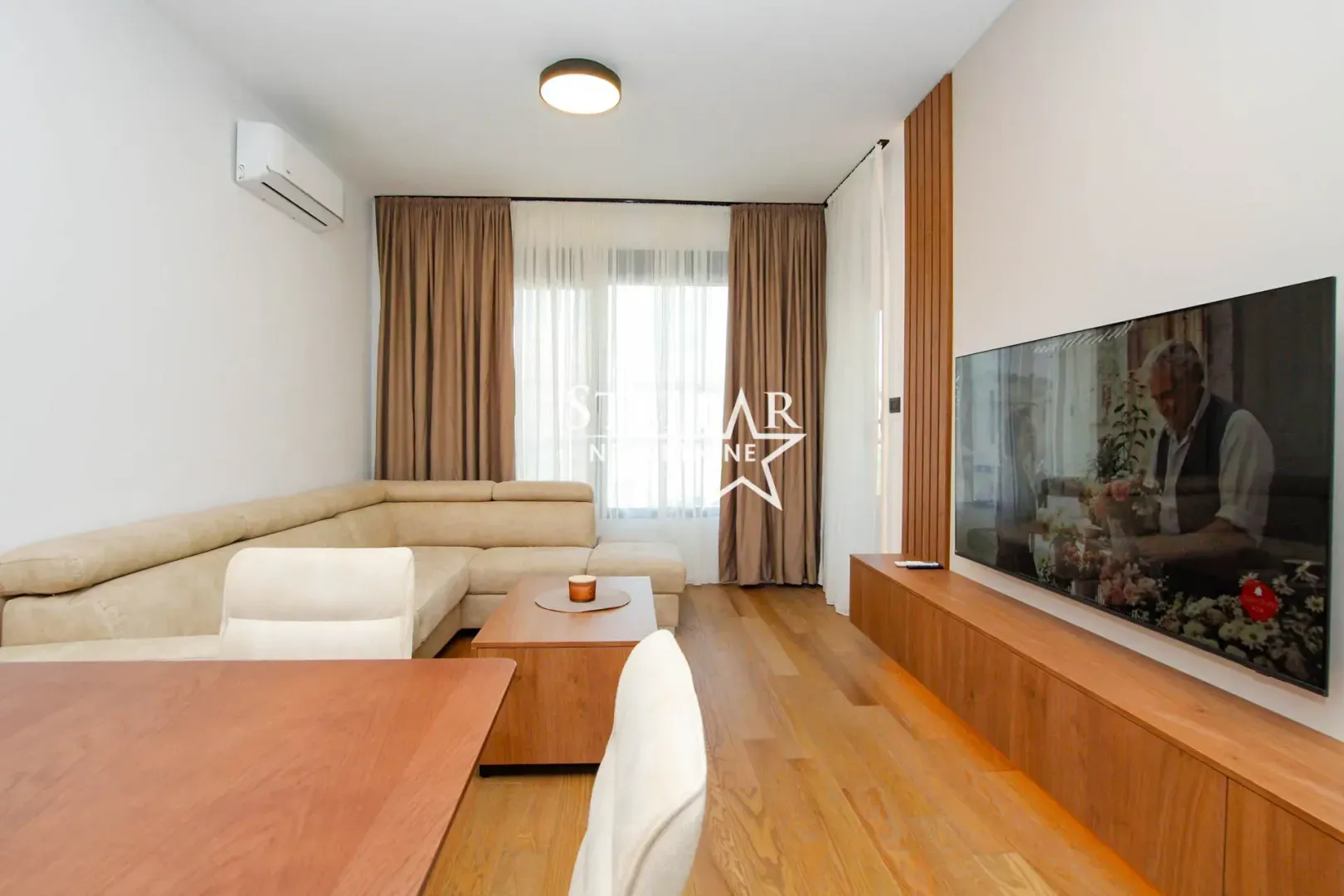 Living room with a sectional sofa, television, and dining table.
