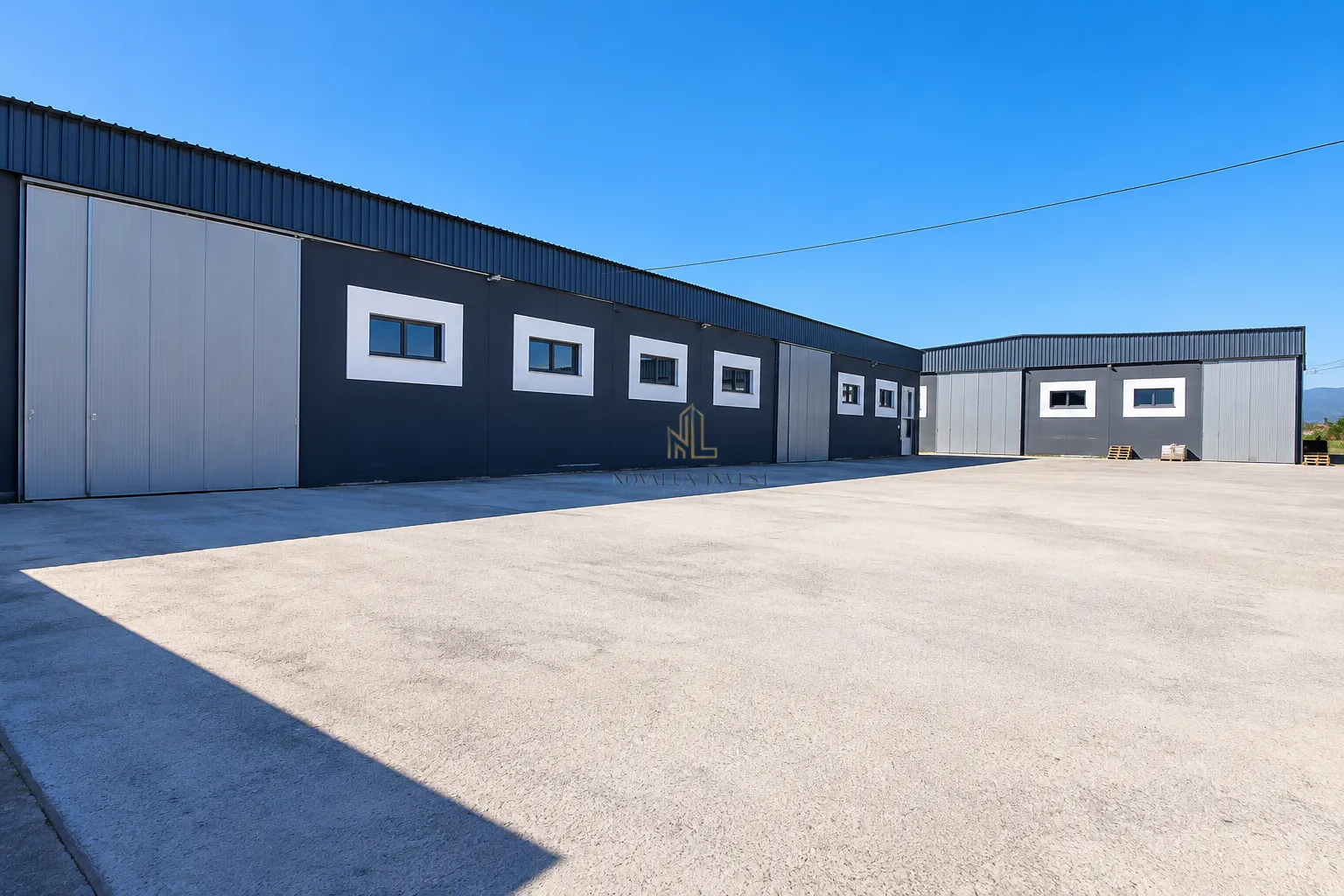 Exterior of a commercial building with a large paved yard and industrial doors.