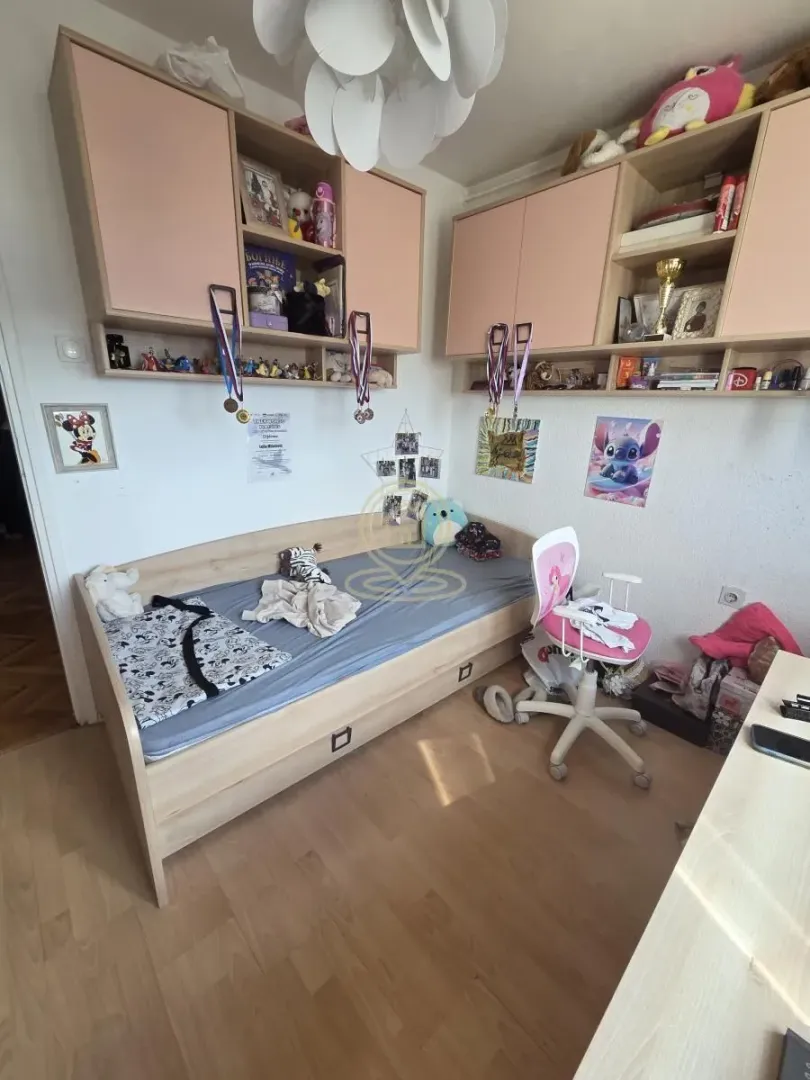 Children's bedroom with a bed, desk, and wall-mounted cabinets.