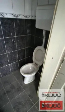 View of the bathroom with a toilet and dark tiles. - image 9