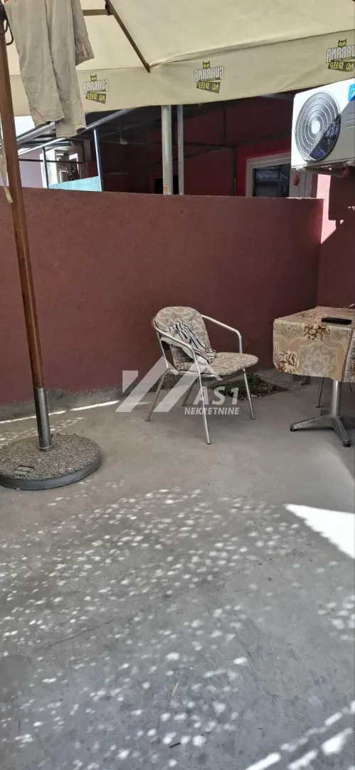Terasa sa stolom, stolicama i suncobranom.