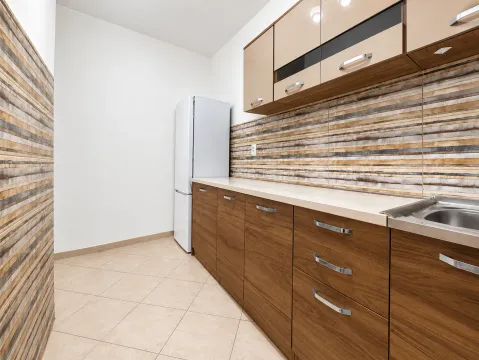 Kuhinja sa drvenim elementima, radnom pločom i frižiderom. - image 8