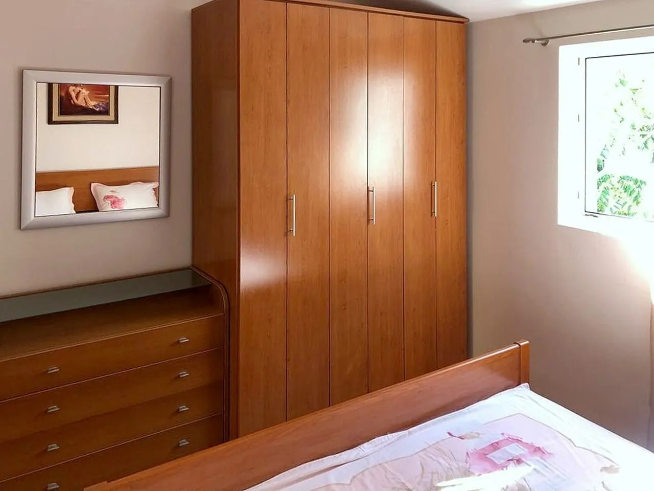 Bedroom with wooden wardrobe, bed and chest of drawers.