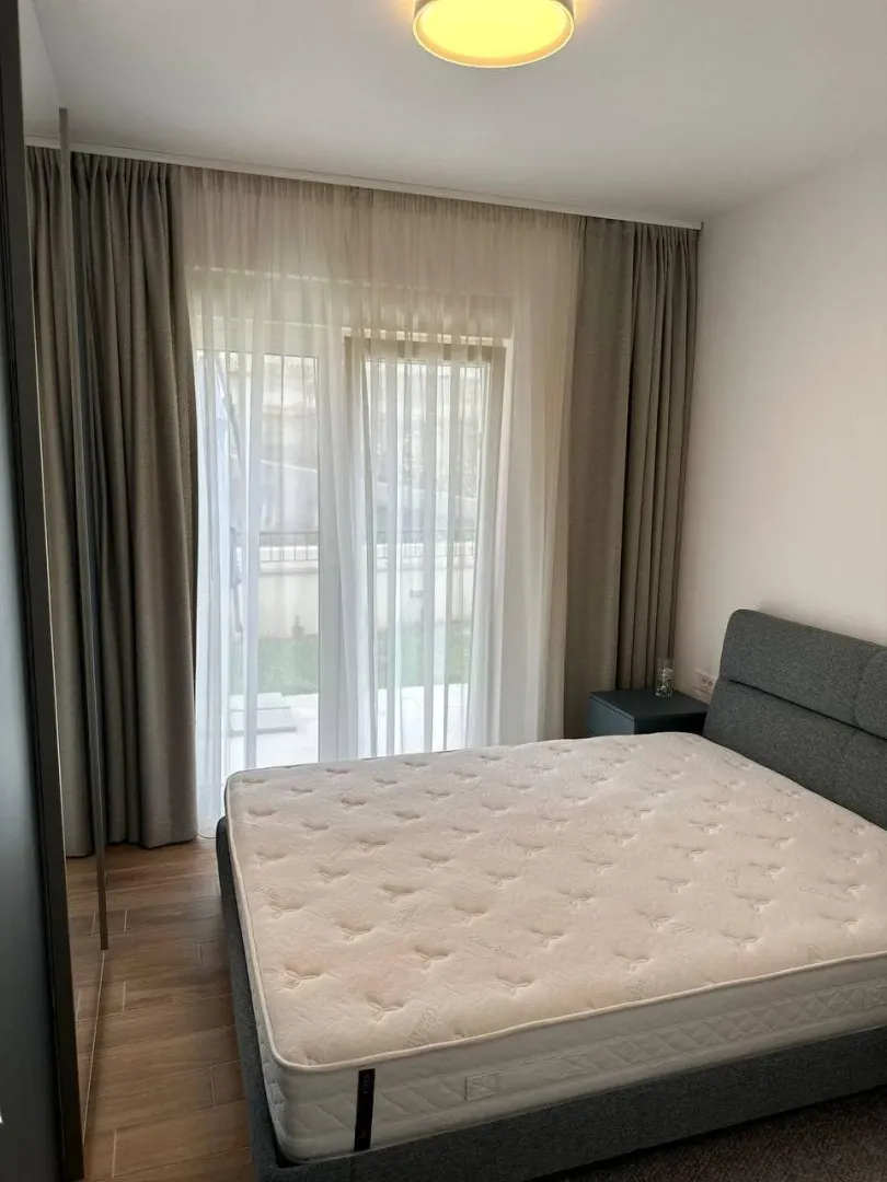 Svijetla spavaća soba sa bračnim krevetom i velikim prozorom.