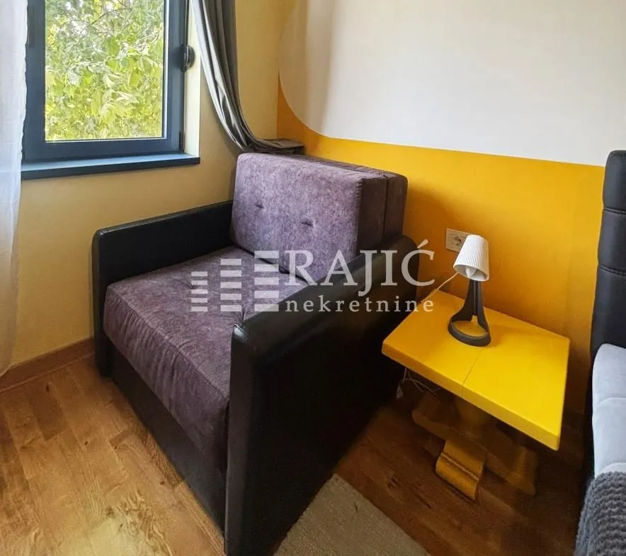 Small room with a pull-out armchair and a yellow bedside table.