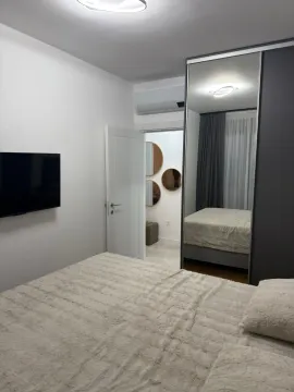 Moderna spavaća soba sa bračnim krevetom, garderoberom sa ogledalom i televizorom na zidu. - image 11