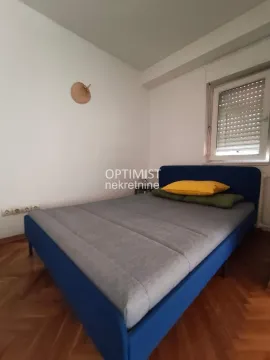 Manja spavaća soba sa plavim krevetom i parketom na podu. - image 8
