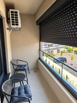 Small furnished balcony with seating set and parking view. - image 13