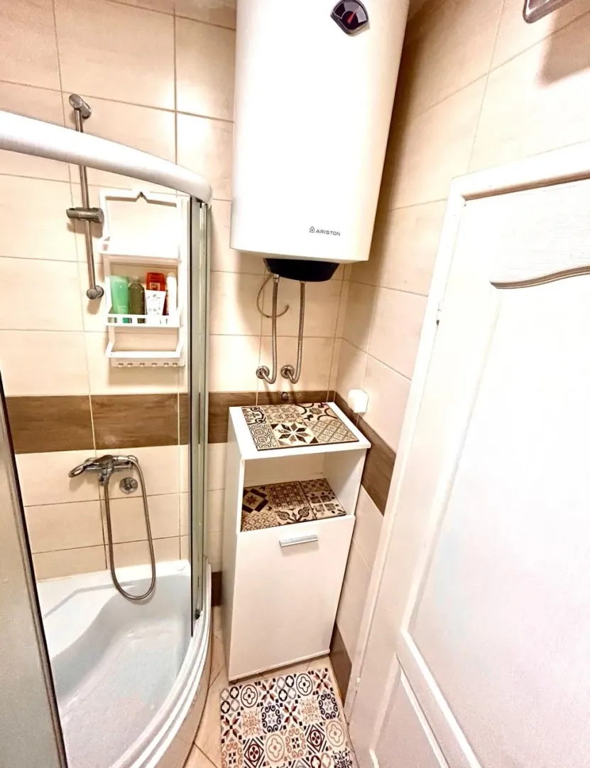 Bathroom with a shower cabin, water heater, and a cabinet.