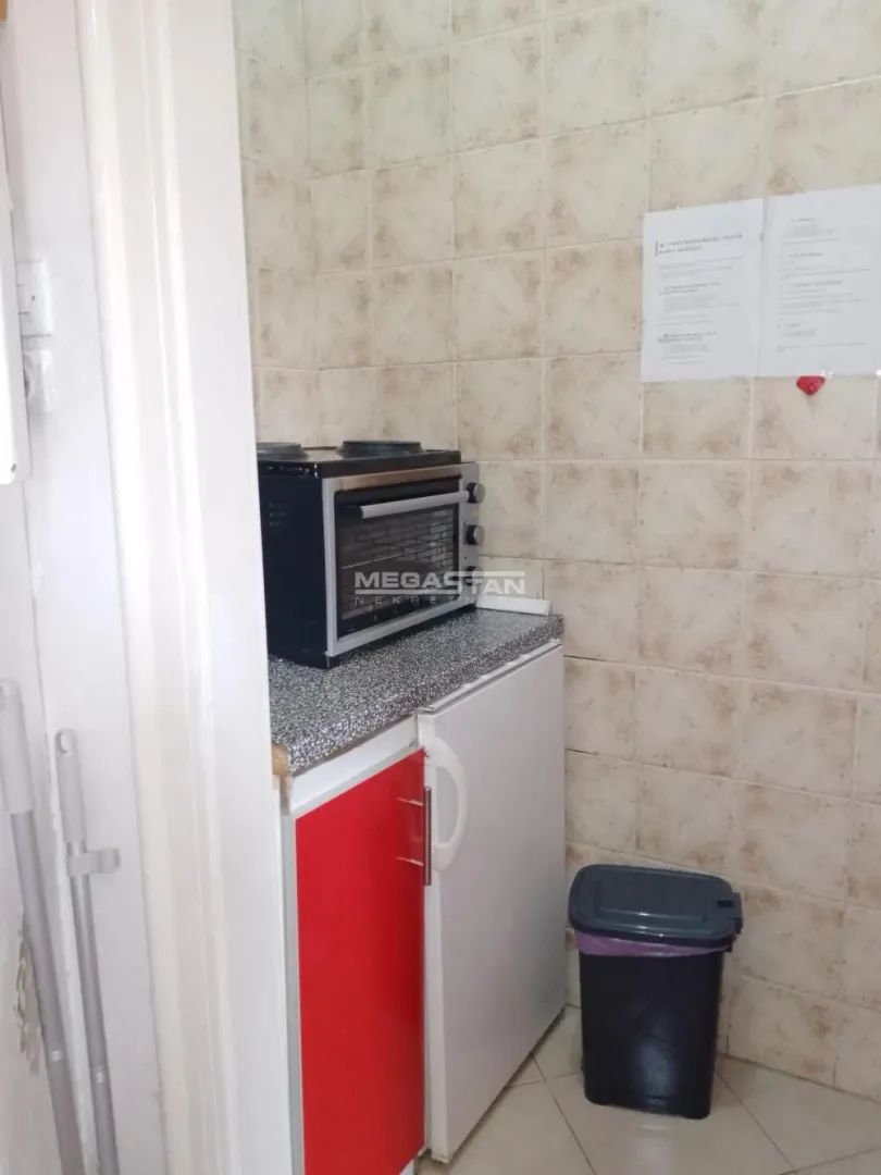 Manja kuhinja sa mini pećnicom, frižiderom i pločicama na zidu.