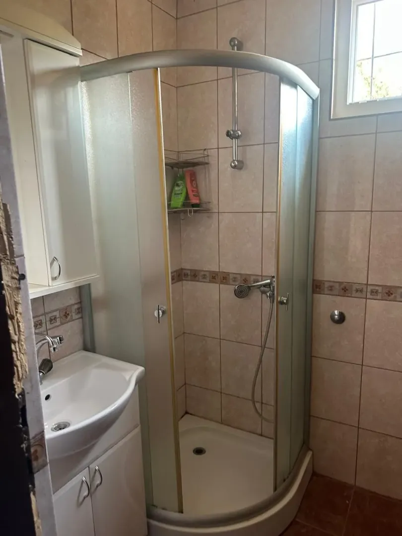Manje kupatilo sa tuš kabinom i umivaonikom.