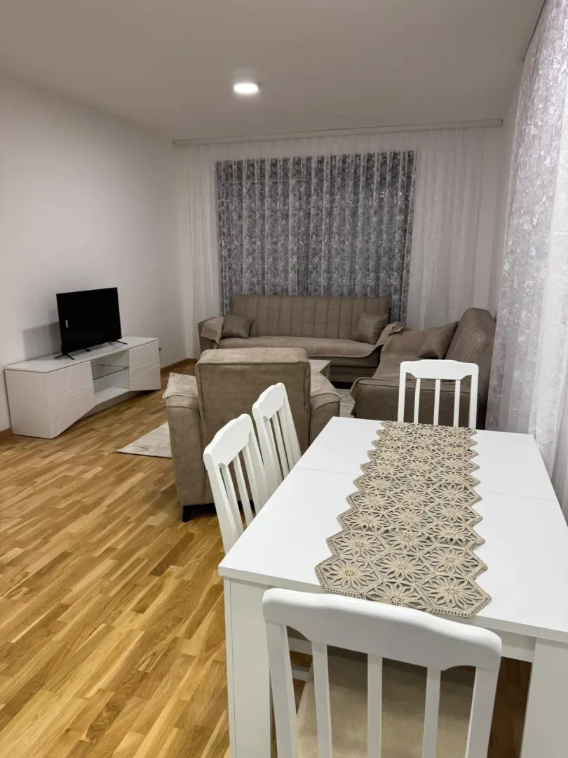 Living room with a sofa set, TV unit, and dining table.