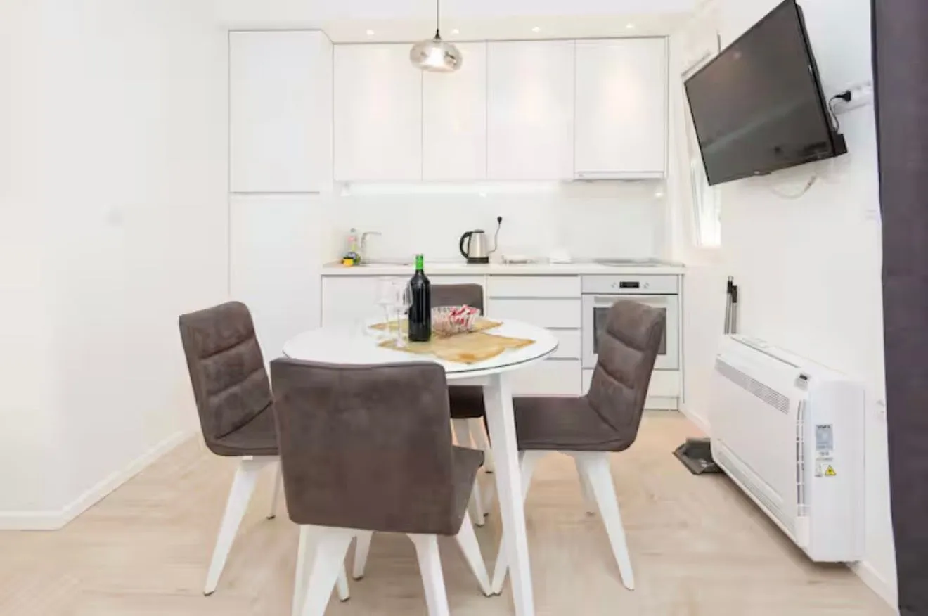 Modern kitchen with a dining table and white cabinets.