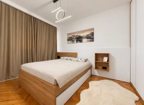 Decorated bedroom with a double bed, wooden flooring, and a large window with curtains. - image 4