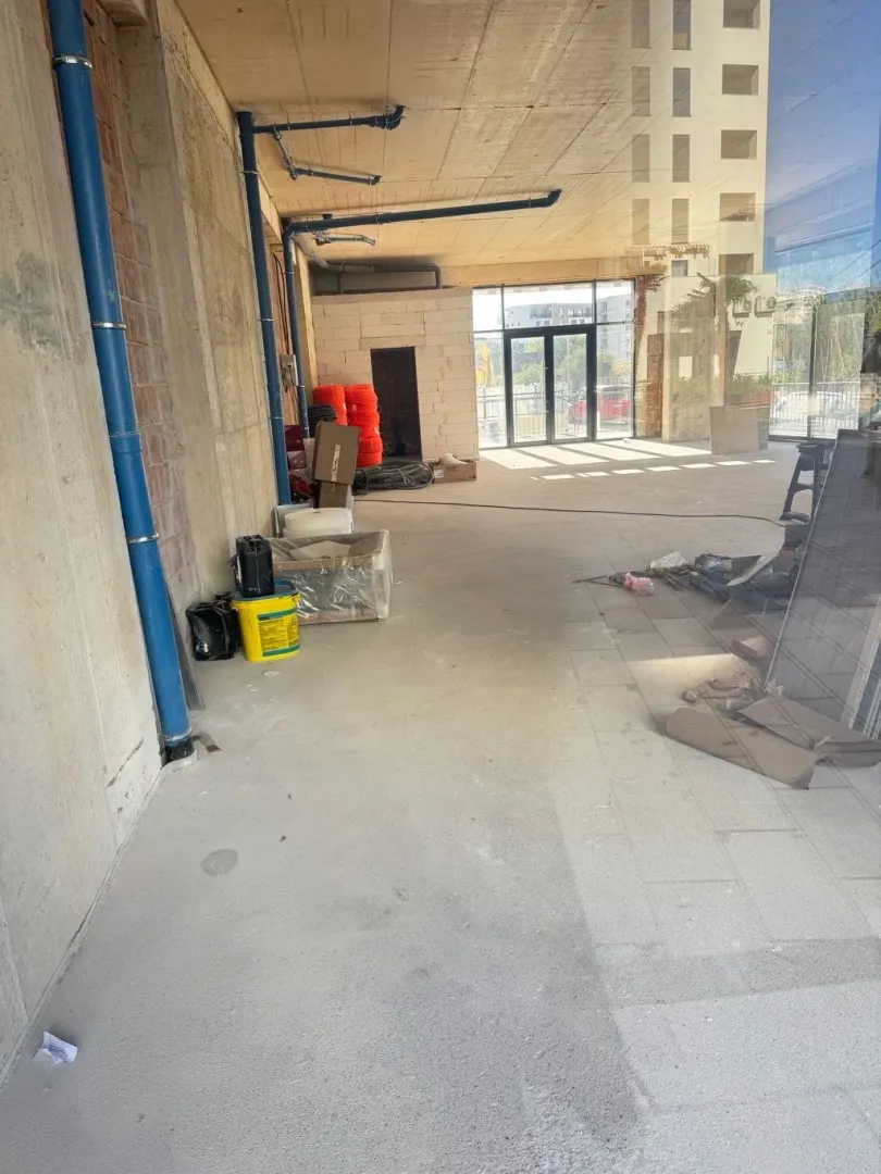 Empty space under construction with concrete floor and installations.