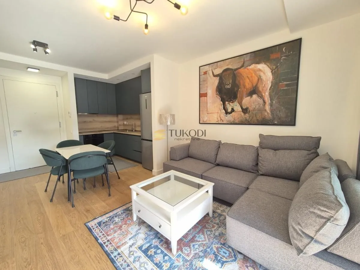 Living room with a sectional sofa, dining area, and kitchen in the background.