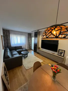 Living room with sofa, TV unit, and dining table in the foreground. - image 4
