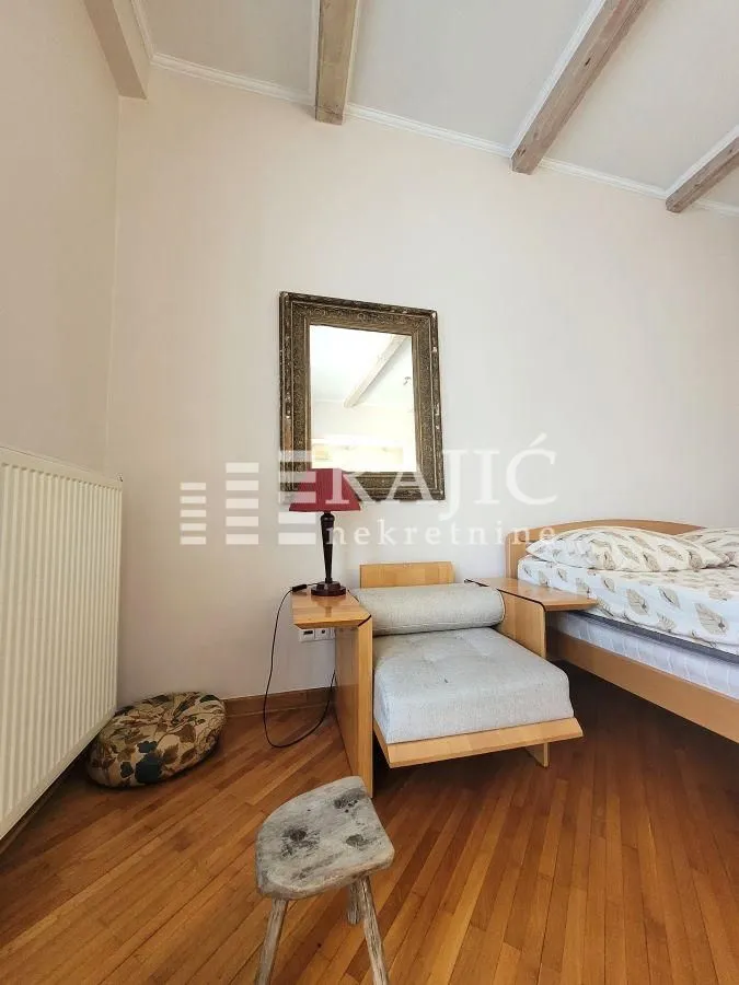 Bedroom with a bed, armchair, and wall mirror.