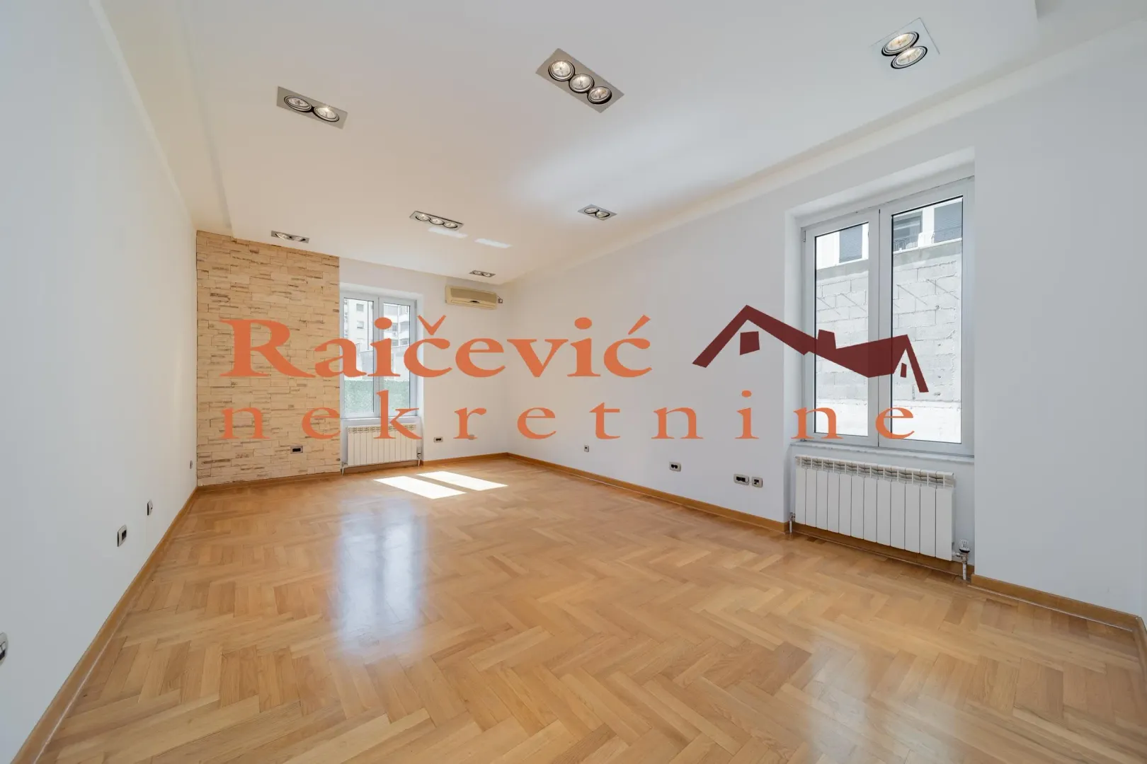 Empty living room with parquet flooring and white walls.