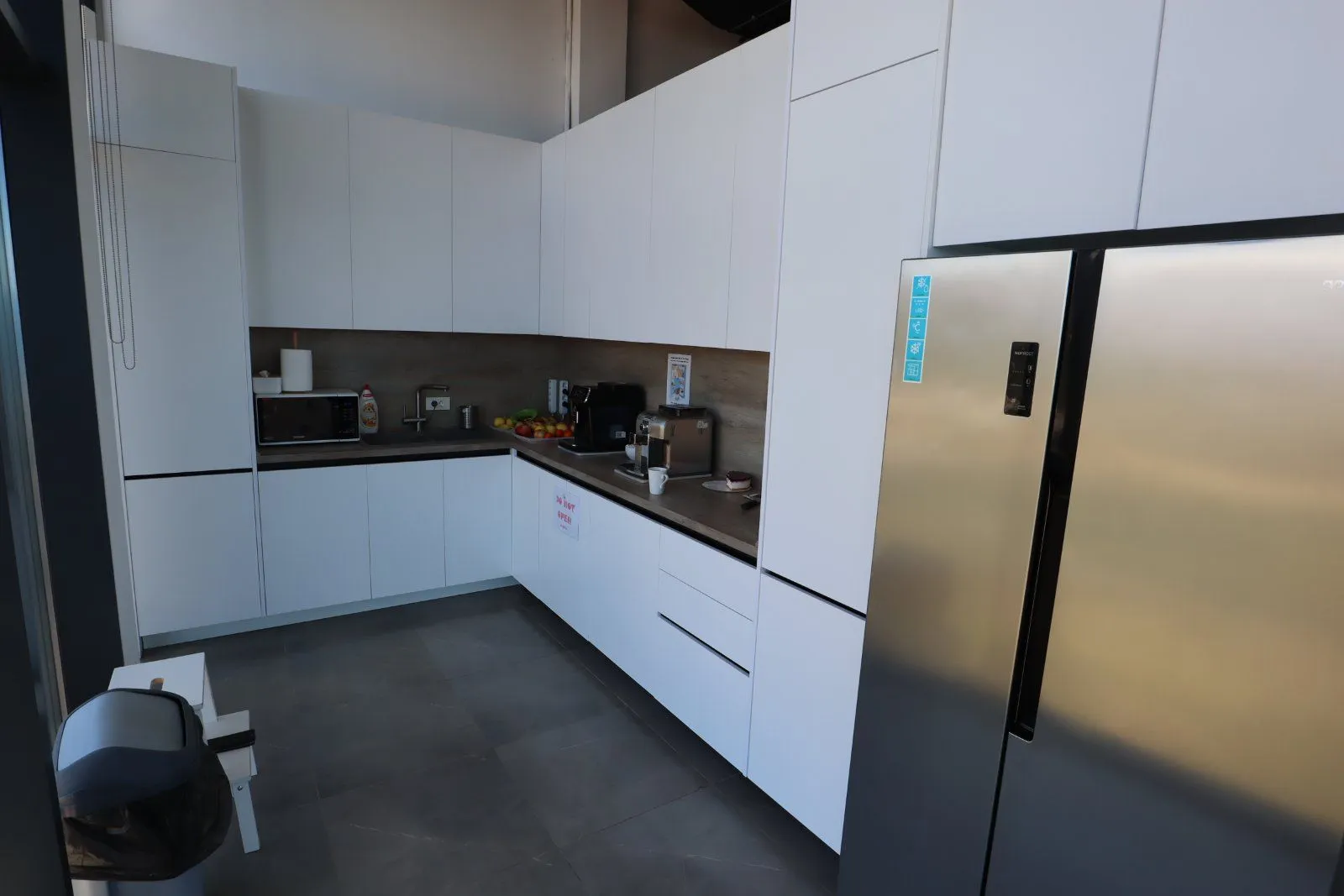 Modern kitchen with white cabinetry and a large refrigerator.