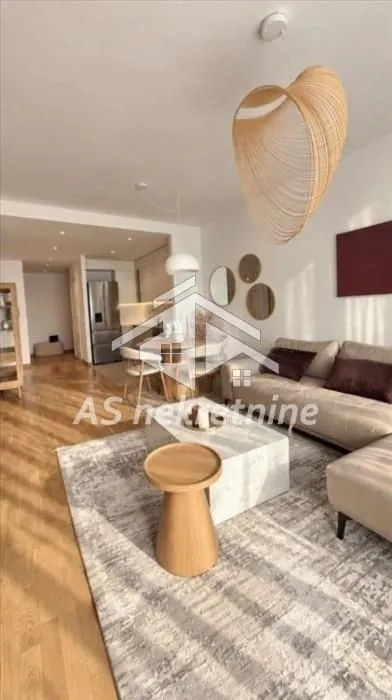 Living room with a sofa, coffee table, and a view of the dining area and kitchen.
