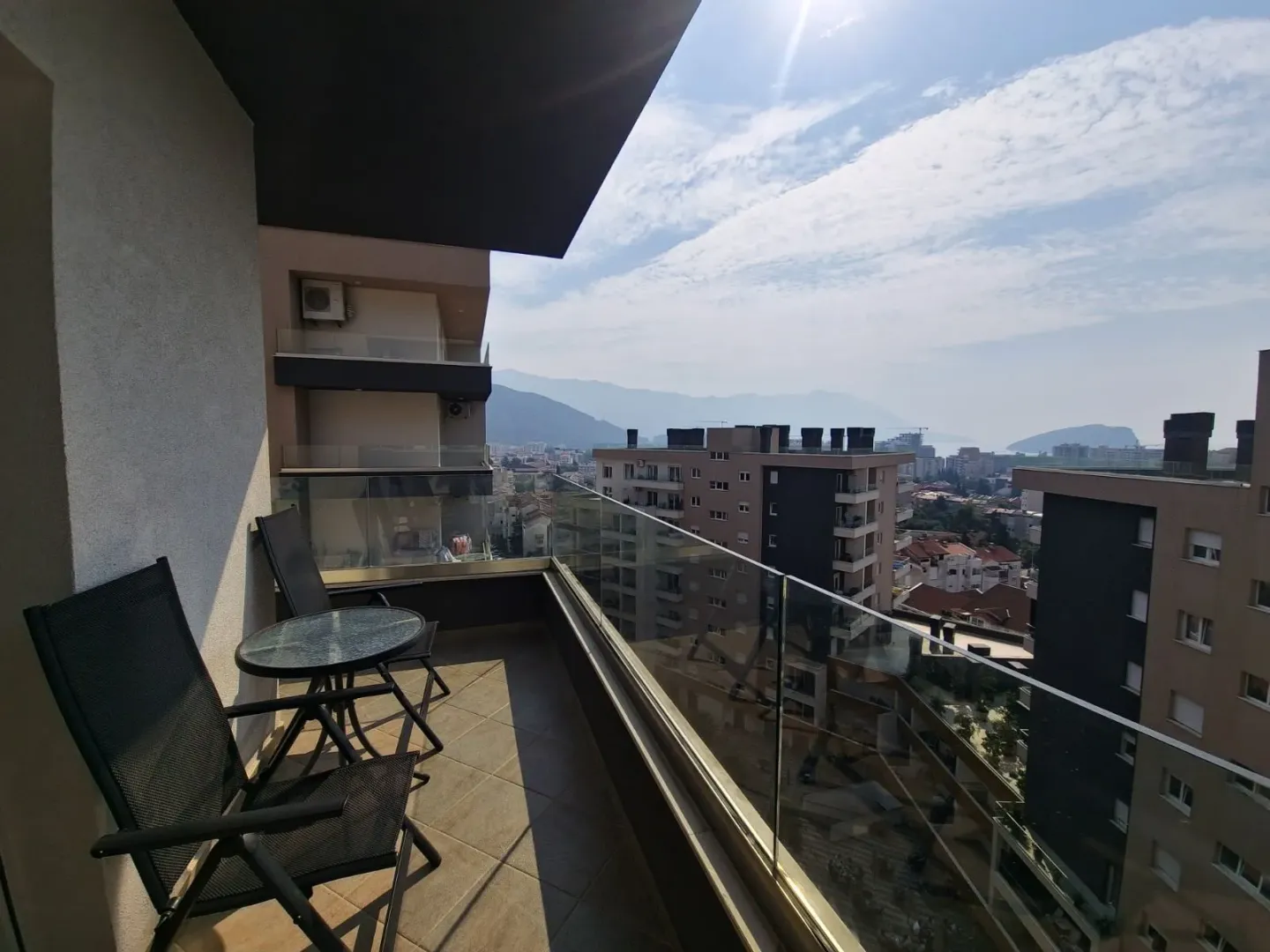 Namješten balkon sa garniturom za sjedenje i pogledom na grad i planine.