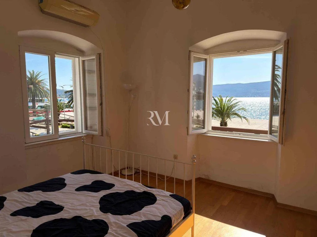 Bedroom with a bed and a sea view through two windows.