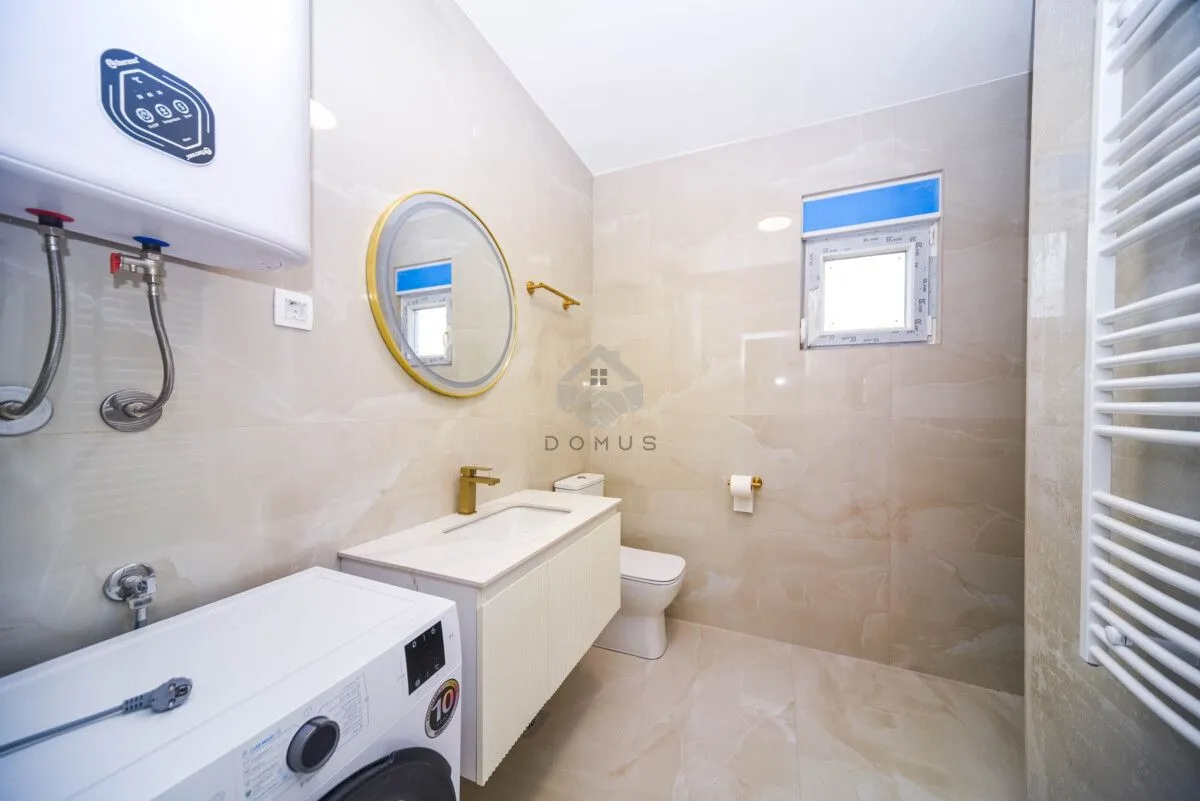 Modernly equipped bathroom with a washbasin, toilet, washing machine, and water heater.
