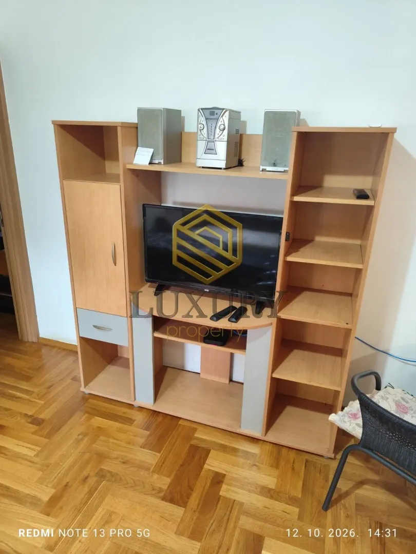 Dnevna soba sa drvenom komodom za televizor.