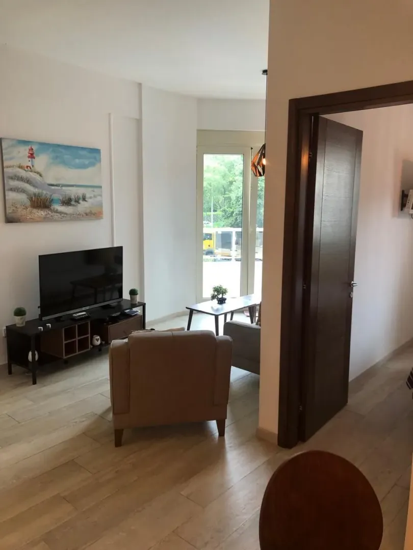 Living room with furniture, television, and balcony access.