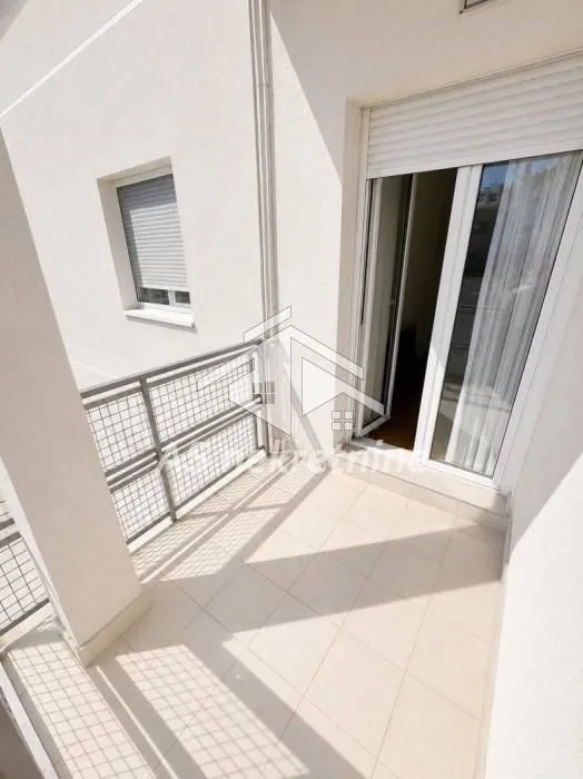 Manji popločani balkon sa metalnom ogradom i izlazom u prostoriju.