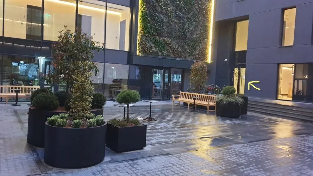 Interior courtyard of the building with paved flooring, potted greenery, and benches for sitting.