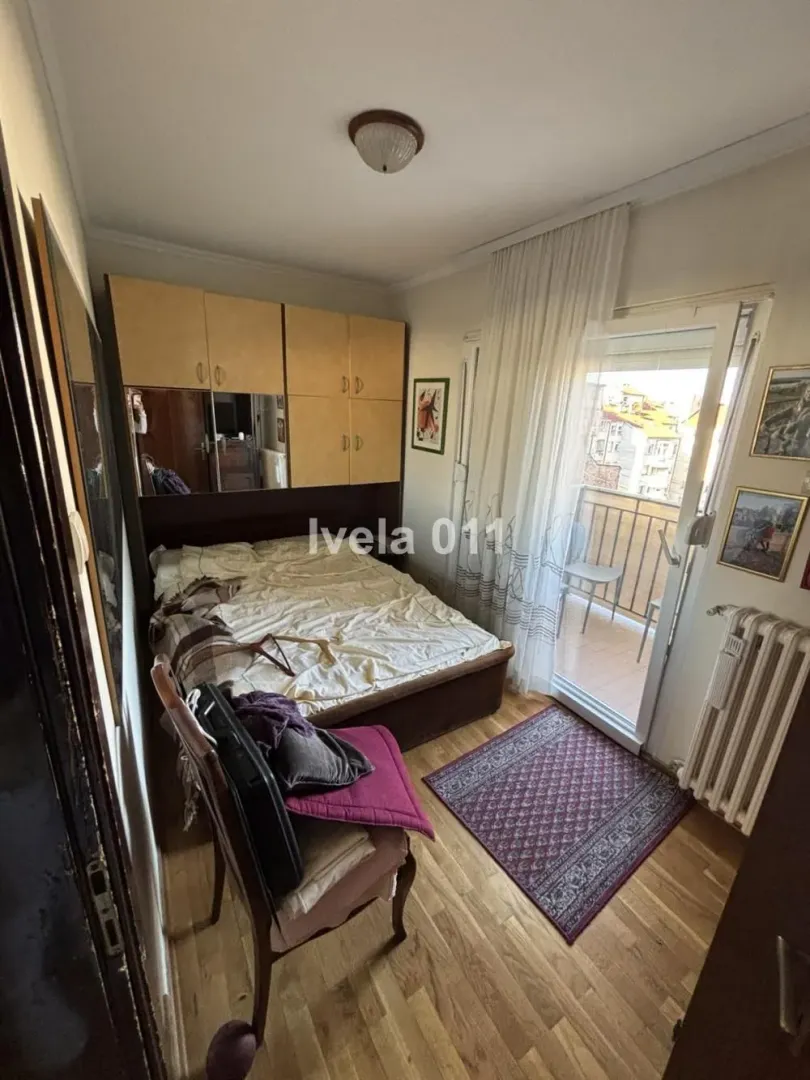 Nameštena spavaća soba sa bračnim krevetom i izlazom na terasu.