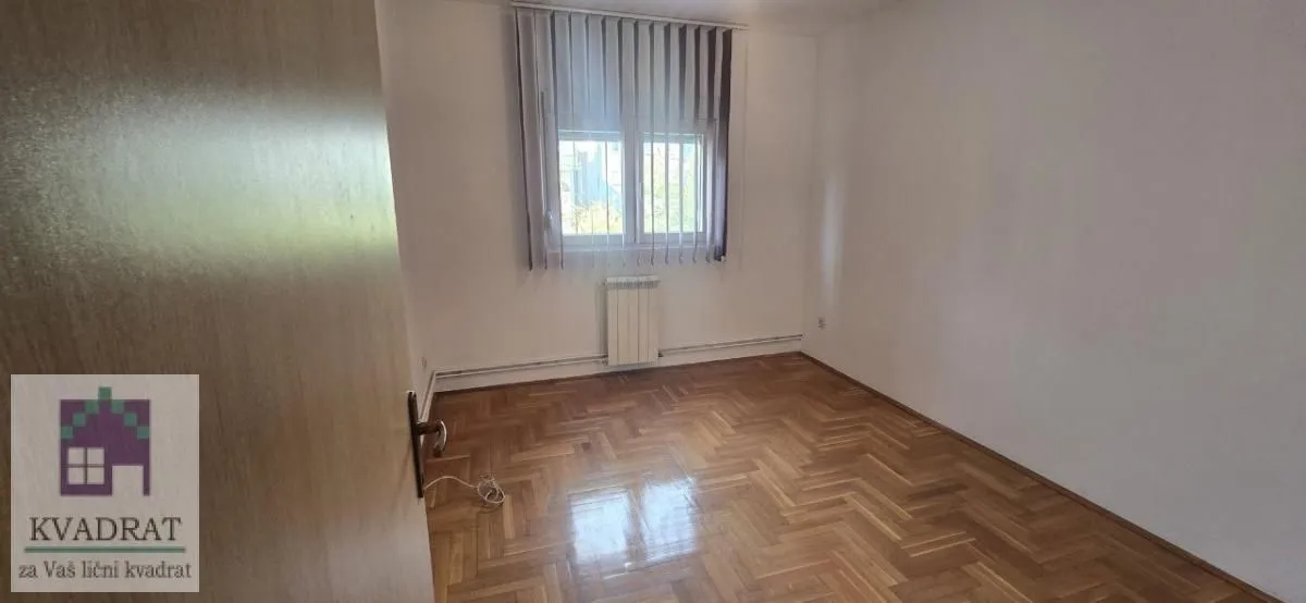 Prazna soba sa parketom i prozorom.