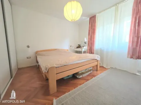 Spavaća soba sa bračnim krevetom, drvenim podom i prozorom sa zavesama. - image 11