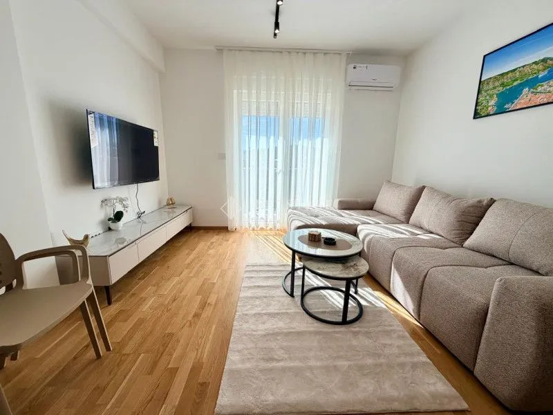 Bright living room with a sofa, TV, and access to the terrace.