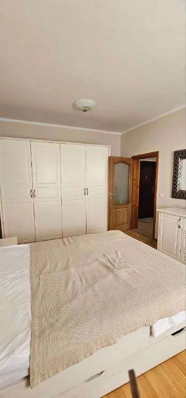 Spavaća soba sa velikim bračnim krevetom, bijelim garderoberom i vratima koja vode u hodnik.