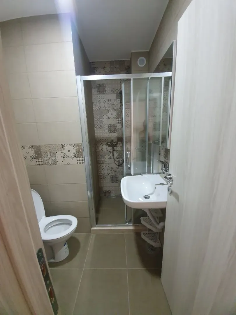 Smaller bathroom with a shower cabin, washbasin, and toilet.