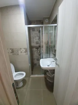Smaller bathroom with a shower cabin, washbasin, and toilet. - image 8