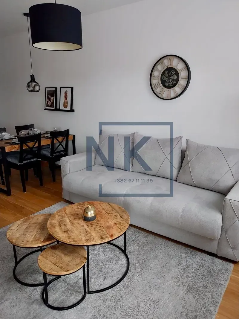 Living room with a grey sofa, wooden coffee table, and a dining area in the background.