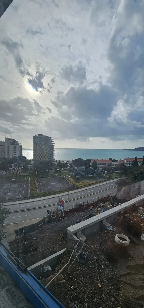 Pogled sa terase na grad, saobraćajnicu i more u daljini.