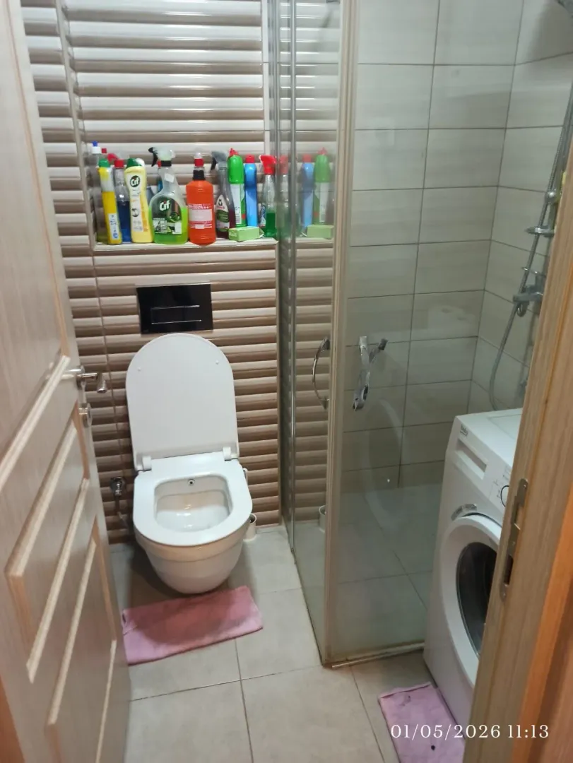 Manje kupatilo sa tuš kabinom, WC šoljom i veš mašinom.