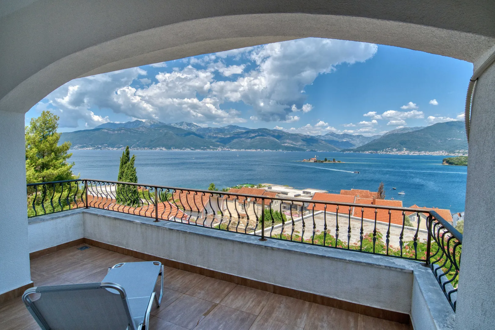 Natkriveni balkon sa ležaljkom i pogledom na more i planine.