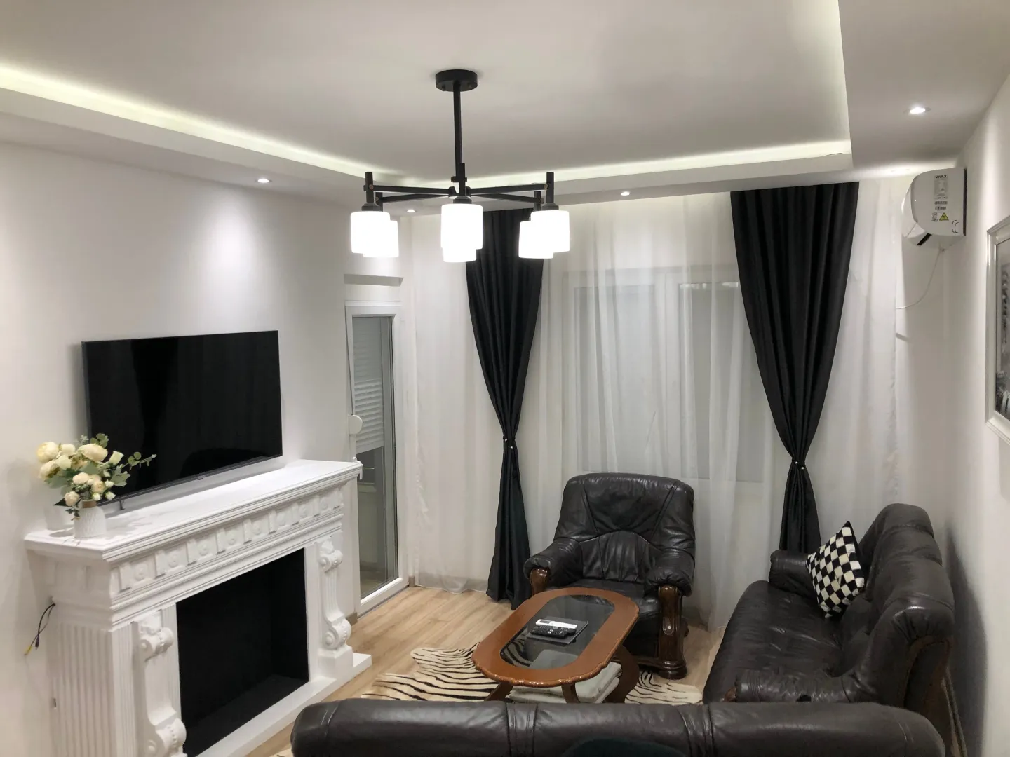 Living room with sofa set, fireplace, and television.