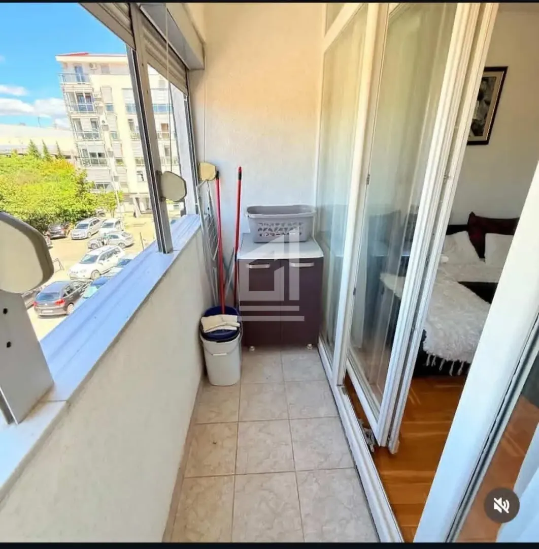 Zastakljeni balkon sa pogledom na ulicu i parking.
